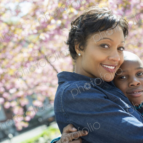 A New York city park in the spring. Sunshine and cherry blossom. A mother and son…