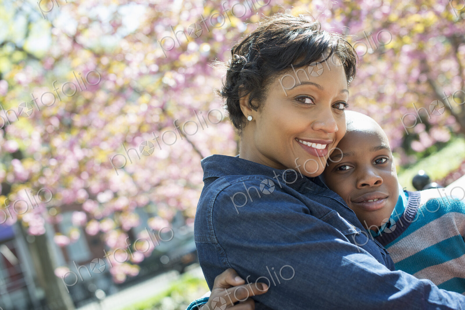 A New York city park in the spring. Sunshine and cherry blossom. A mother and son…