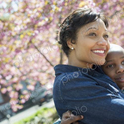 A New York city park in the spring. Sunshine and cherry blossom. A mother and son…