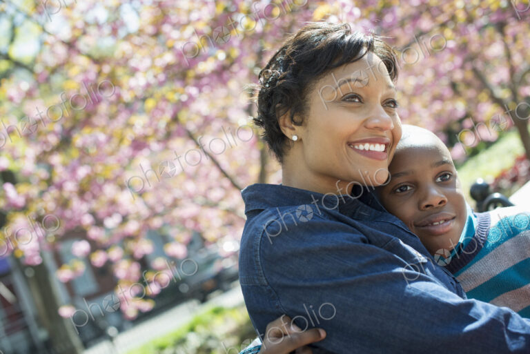A New York city park in the spring. Sunshine and cherry blossom. A mother and son…