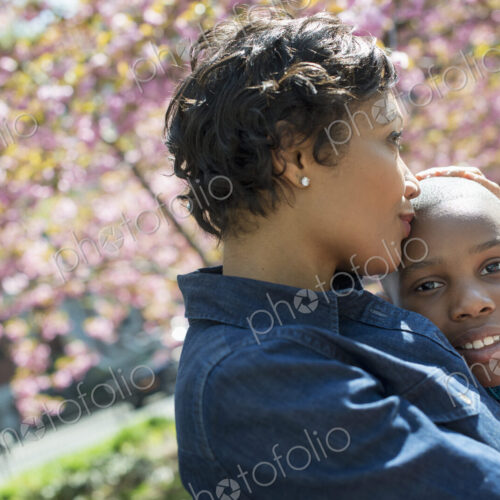 A New York city park in the spring. Sunshine and cherry blossom. A mother and son…