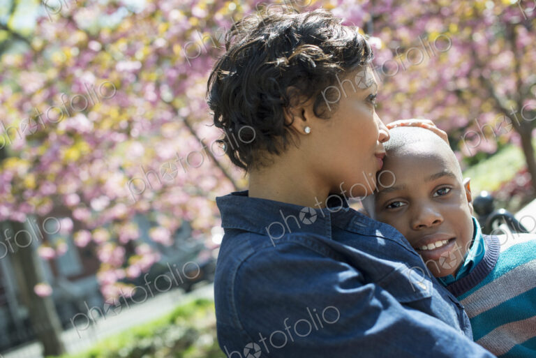 A New York city park in the spring. Sunshine and cherry blossom. A mother and son…