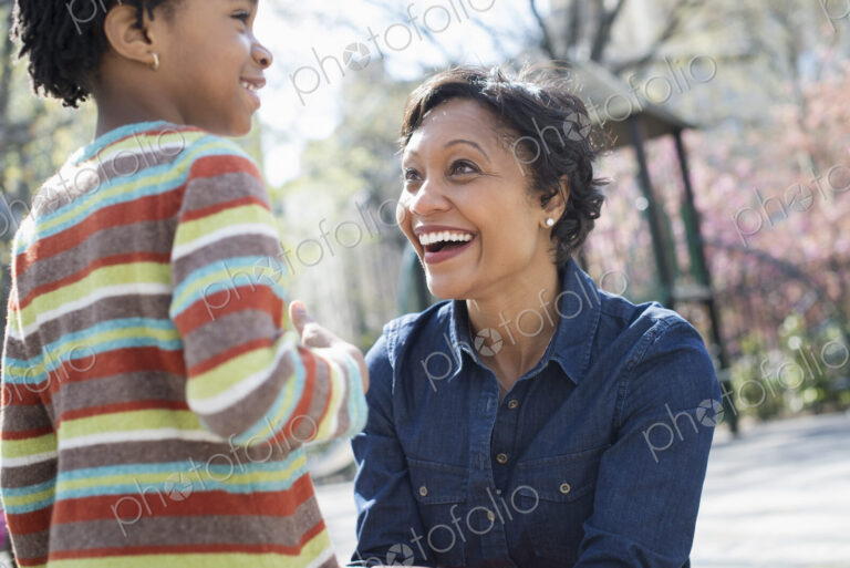 A New York city park in the spring. Sunshine and cherry blossom. A mother kneeling…