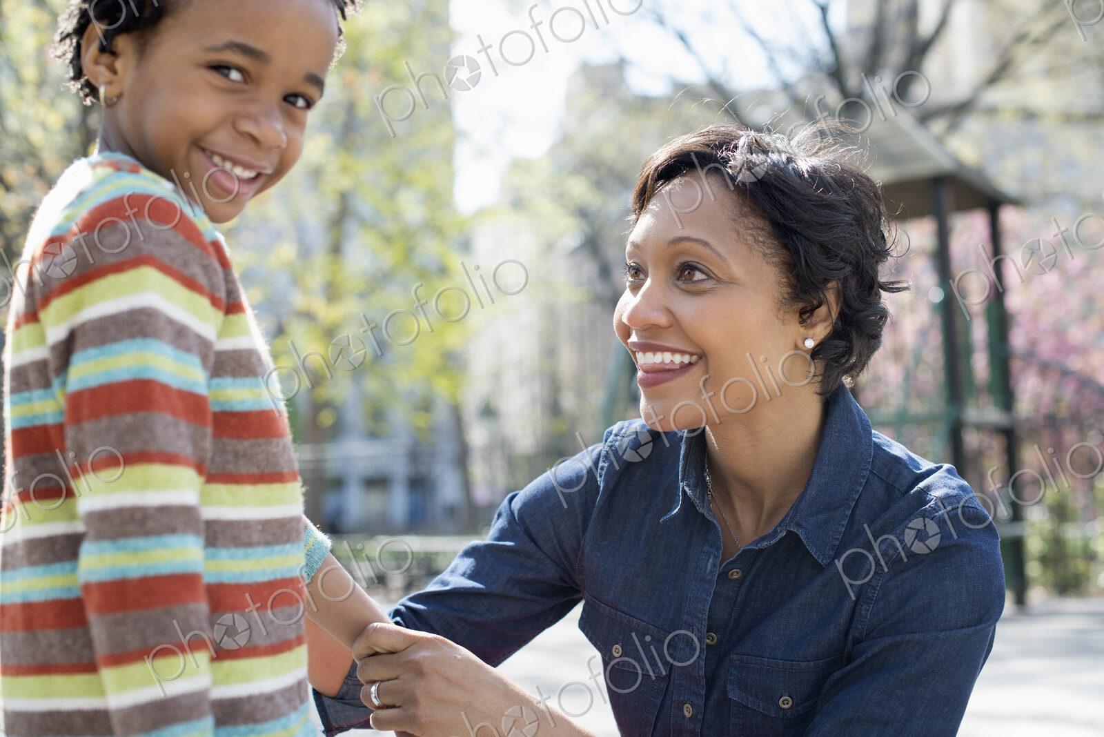 A New York city park in the spring. Sunshine and cherry blossom. A mother kneeling…