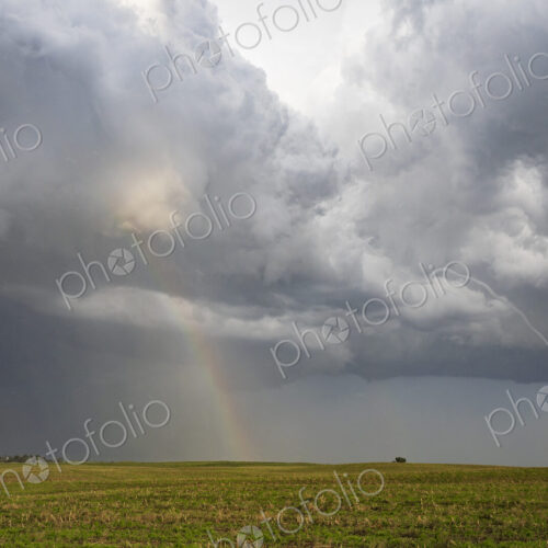 A Small Rope Tornado and a Double Rainbow in the sky above fields. A Small Rope Tornado and a Double Rainbow in the sky above fields.