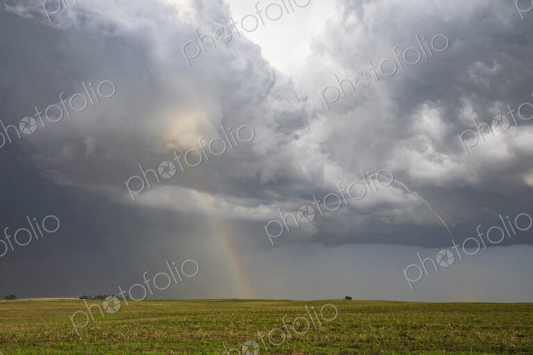 A Small Rope Tornado and a Double Rainbow in the sky above fields.