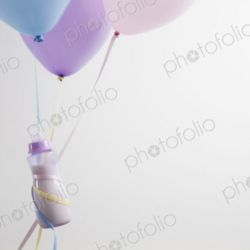 A baby bottles ties with ribbon to three balloons, floating. A baby bottles ties with ribbon to three balloons, floating.