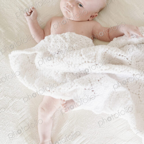 A baby boy lying on his back on a bed. A baby boy lying on his back on a bed.