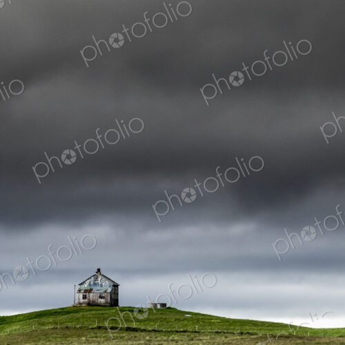 A barn on the crest of a hill, and dark storm clouds glowering over the land. A barn on the crest of a hill, and dark storm clouds glowering over the land.