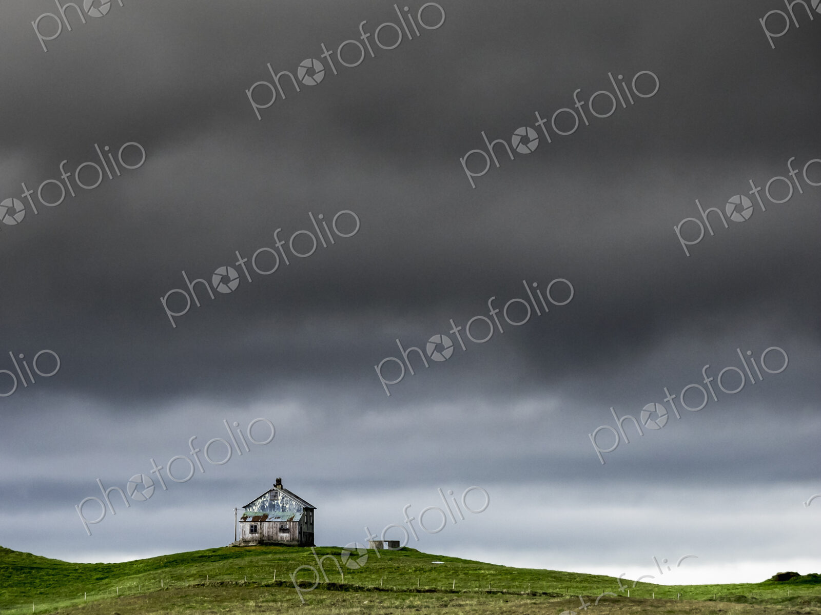 A barn on the crest of a hill, and dark storm clouds glowering over the land.