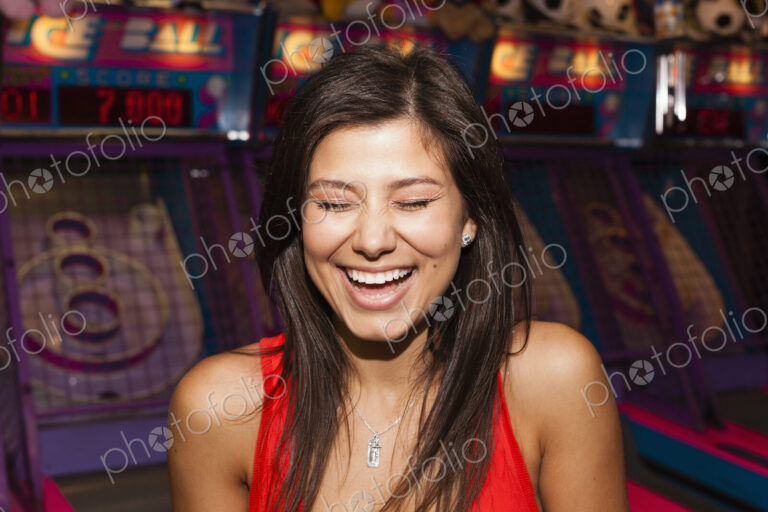 A beautiful young woman on the boardwalk in Atlantic City, in front of a row of slot…
