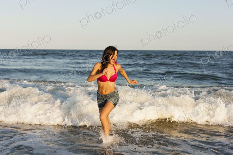 A beautiful young women at the water's edge on the beach in Atlantic City.