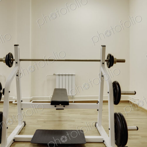 A bench with weight bars in the weights room in a gymnasium.