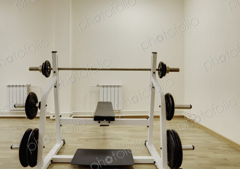 A bench with weight bars in the weights room in a gymnasium.