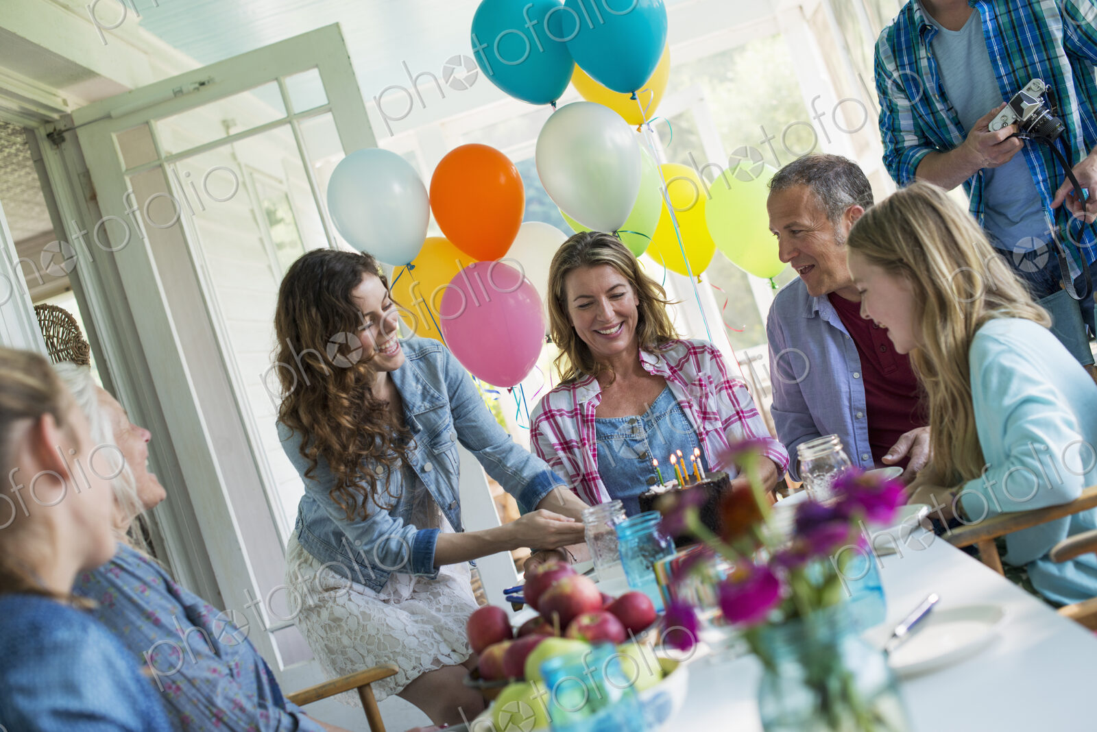 A birthday party in a farmhouse kitchen. A group of adults and children gathered…