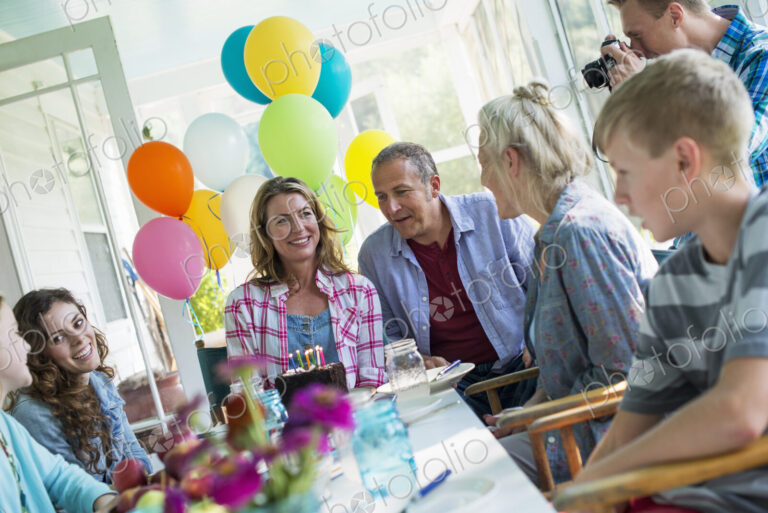 A birthday party in a farmhouse kitchen. A group of adults and children gathered…