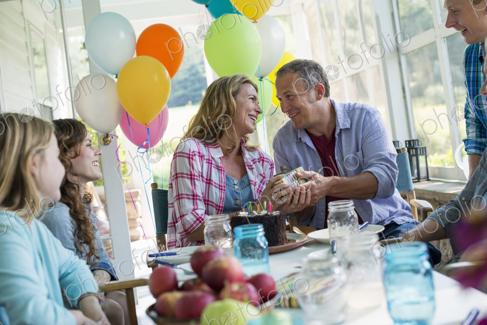 A birthday party in a farmhouse kitchen. A group of adults and children gathered…