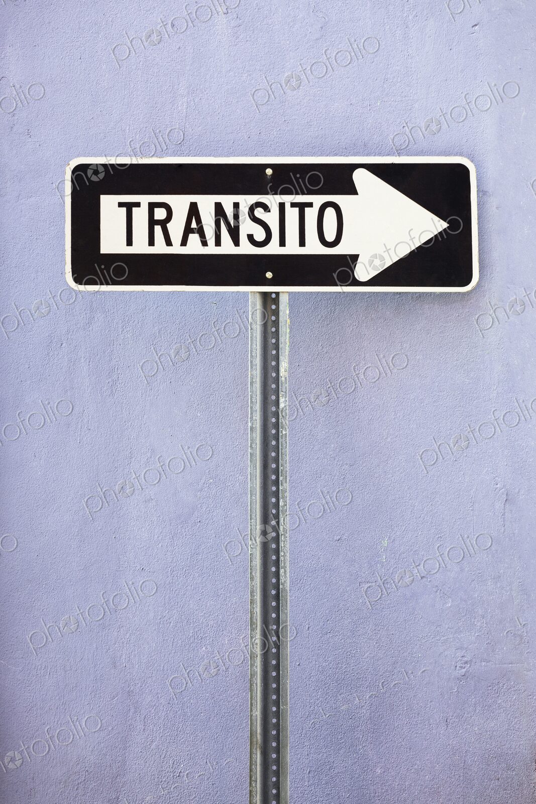 A black and white Spanish-language one-way traffic sign reading Transito is mounted…