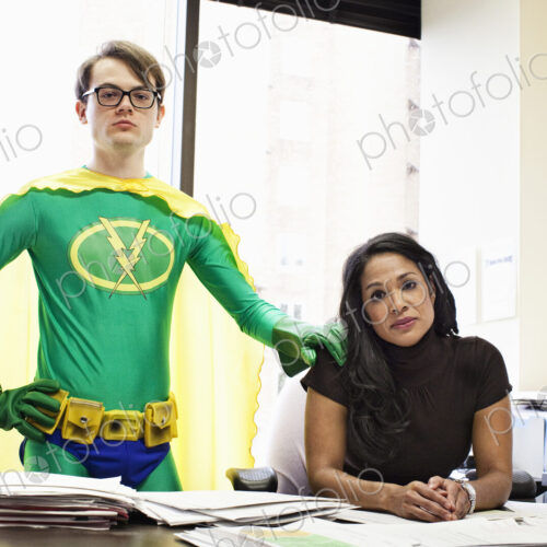 A black business woman at her desk with her caucasian office super hero advisor. A black business woman at her desk with her caucasian office super hero advisor.