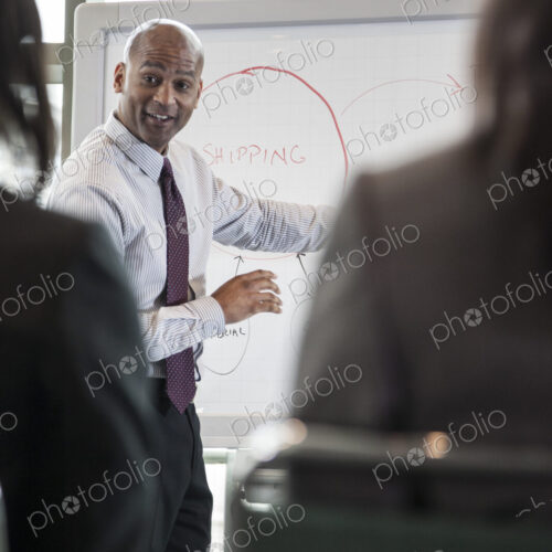 A black businessman leading a meeting standing at a white board. A black businessman leading a meeting standing at a white board.