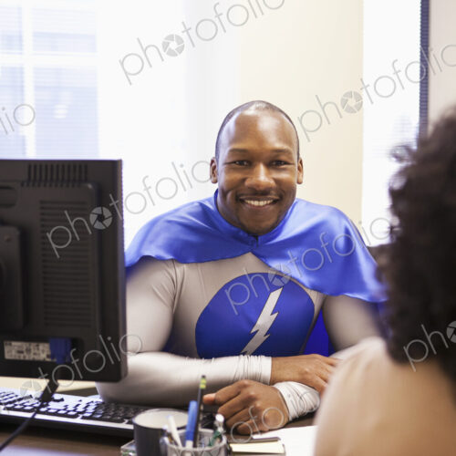 A black businessman office super hero in a meeting with an office tream member.