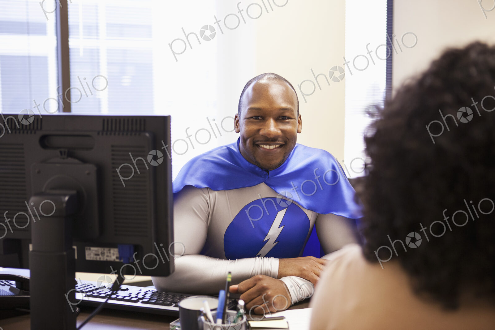 A black businessman office super hero in a meeting with an office tream member.