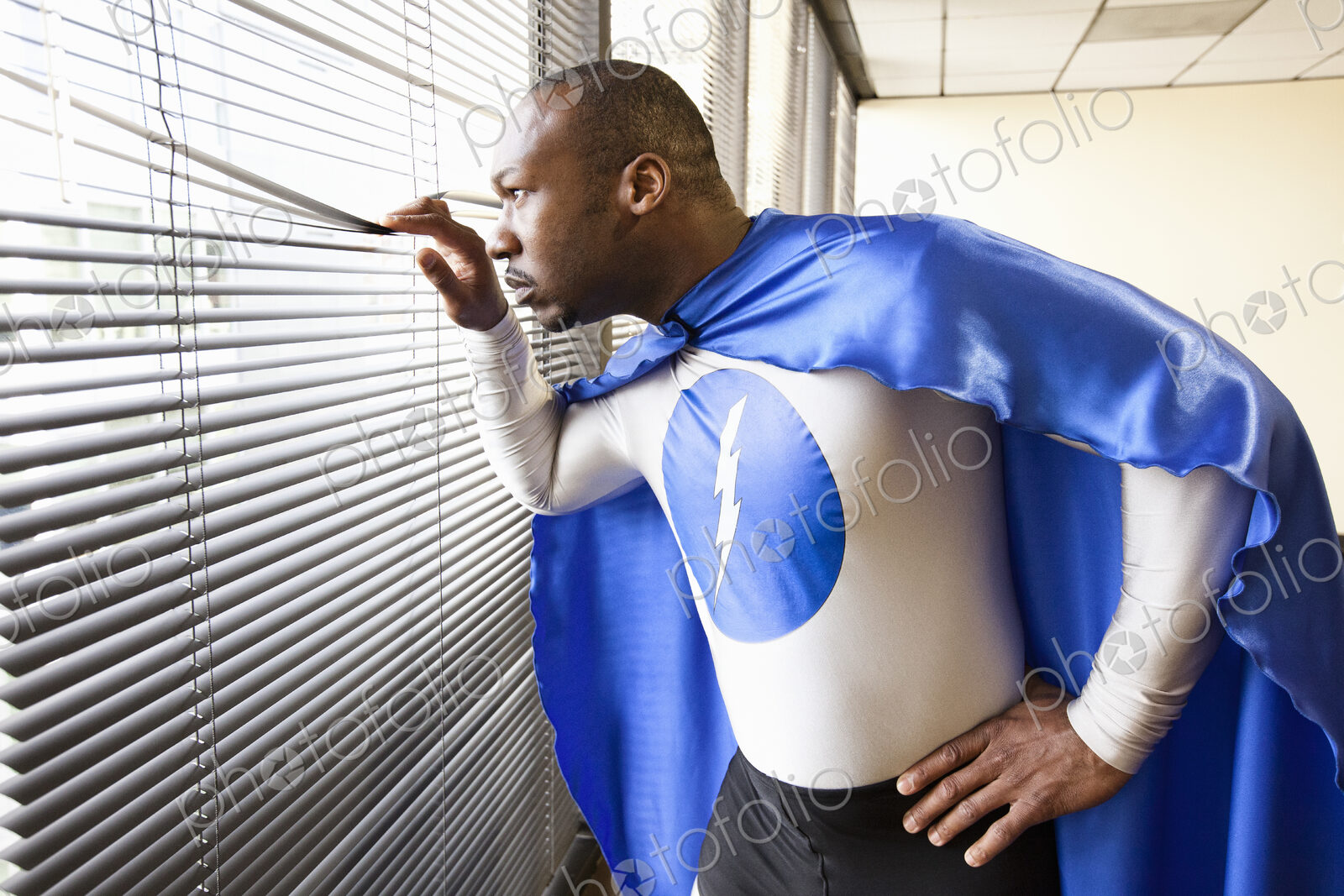 A black businessman office super hero looks out the window and checks his next…