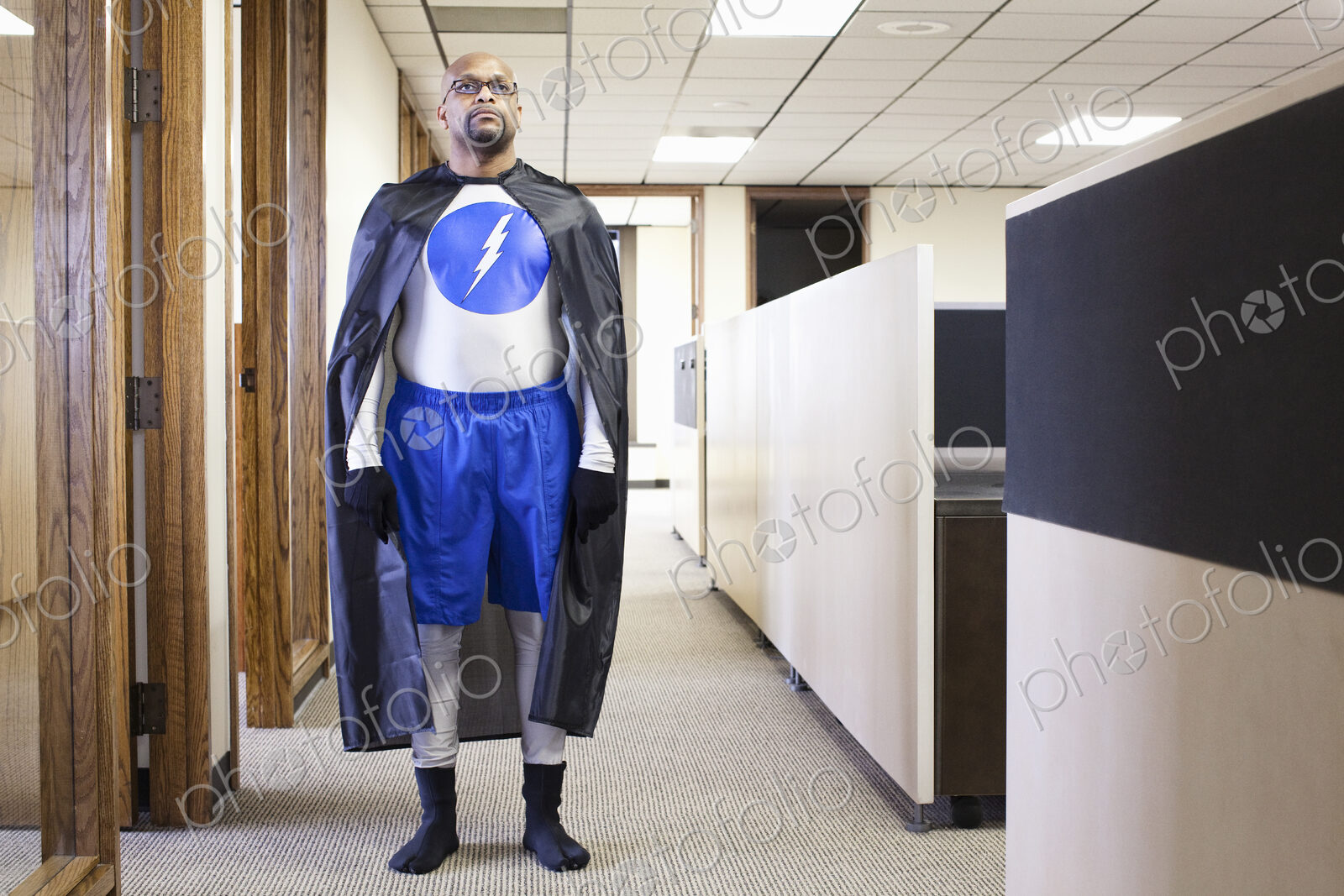 A black businessman office super hero standing in an office hallway.