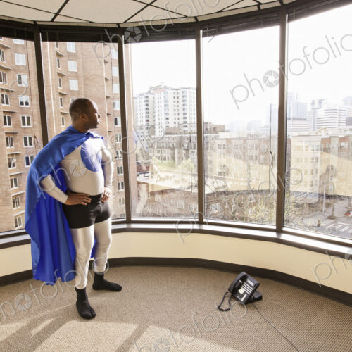 A black businessman office super hero stands at an office window and ponders his next… A black businessman office super hero stands at an office window and ponders his next…