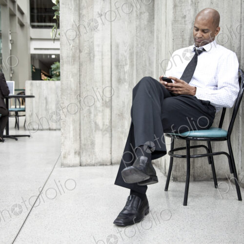 A black businessman texing on his cell phone.