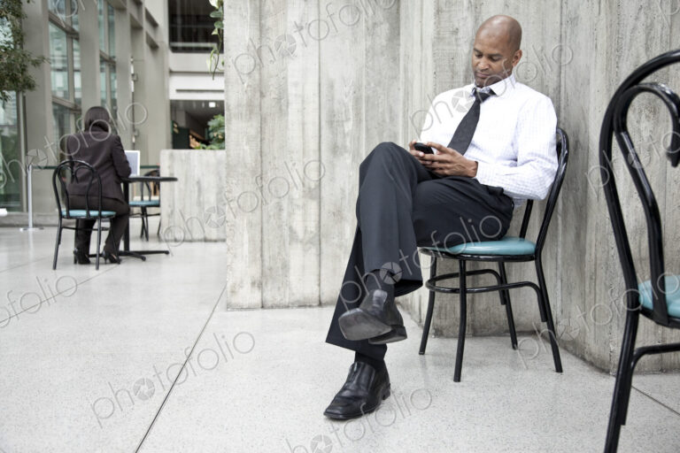 A black businessman texing on his cell phone.