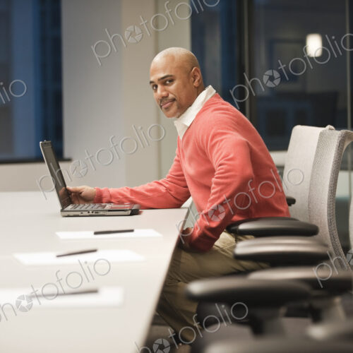A black businessman working at a conference table at night.