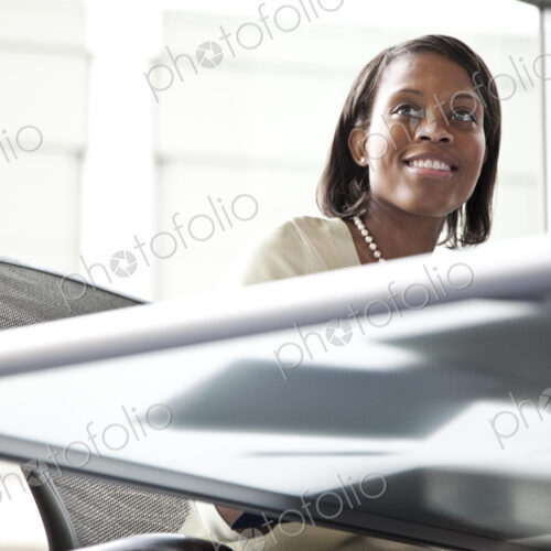 A black businesswoman listening during a meeting in a convention center meeting room.