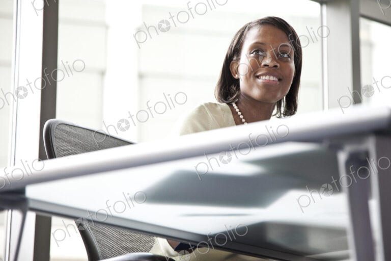 A black businesswoman listening during a meeting in a convention center meeting room.