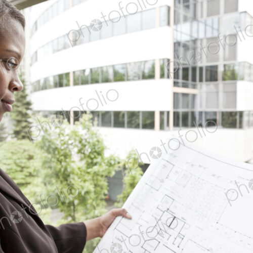 A black businesswoman looking at plans for a new office A black businesswoman looking at plans for a new office