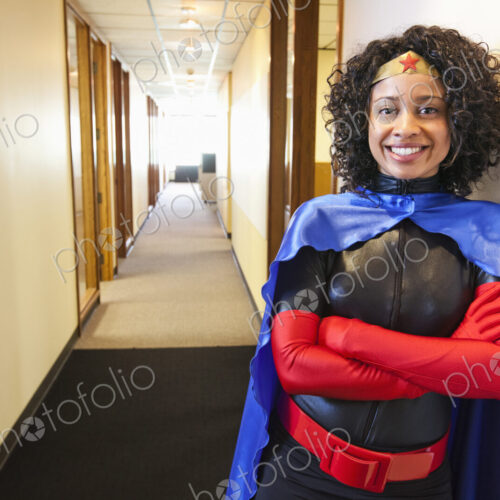 A black businesswoman office super hero standing in a hallway of her office. A black businesswoman office super hero standing in a hallway of her office.