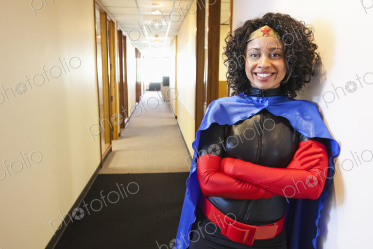 A black businesswoman office super hero standing in a hallway of her office.