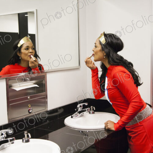 A black businesswoman office super hero takes a make up break between super hero feats. A black businesswoman office super hero takes a make up break between super hero feats.