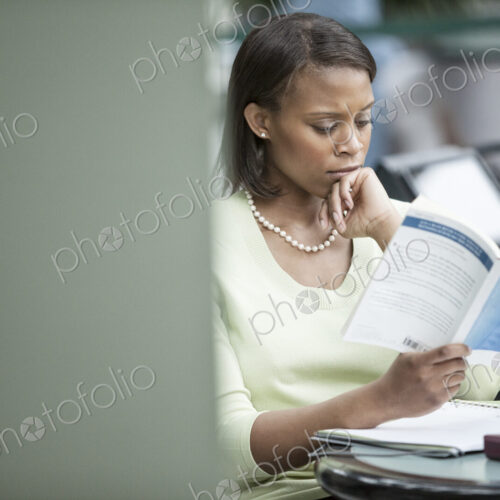 A black businesswoman reading a report. A black businesswoman reading a report.