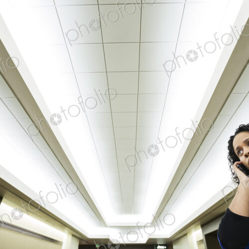 A black businesswoman talkming on the phone while standing in a convention center lobby. A black businesswoman talkming on the phone while standing in a convention center lobby.