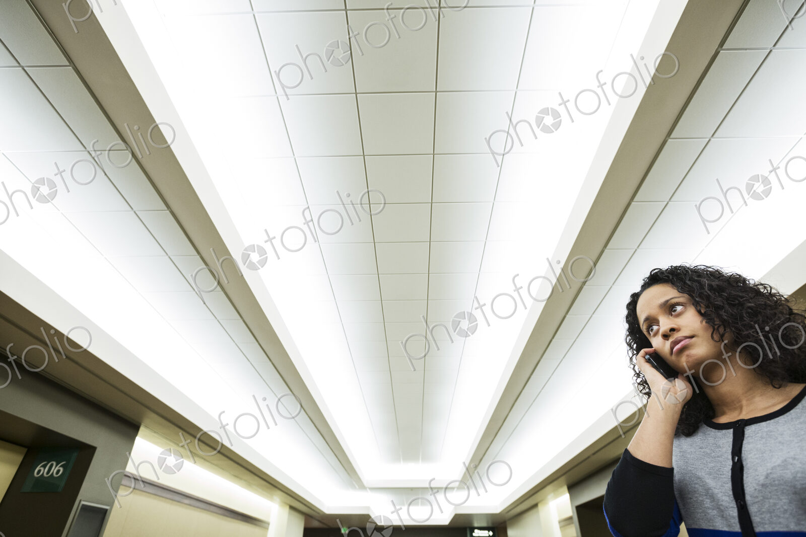 A black businesswoman talkming on the phone while standing in a convention center lobby.