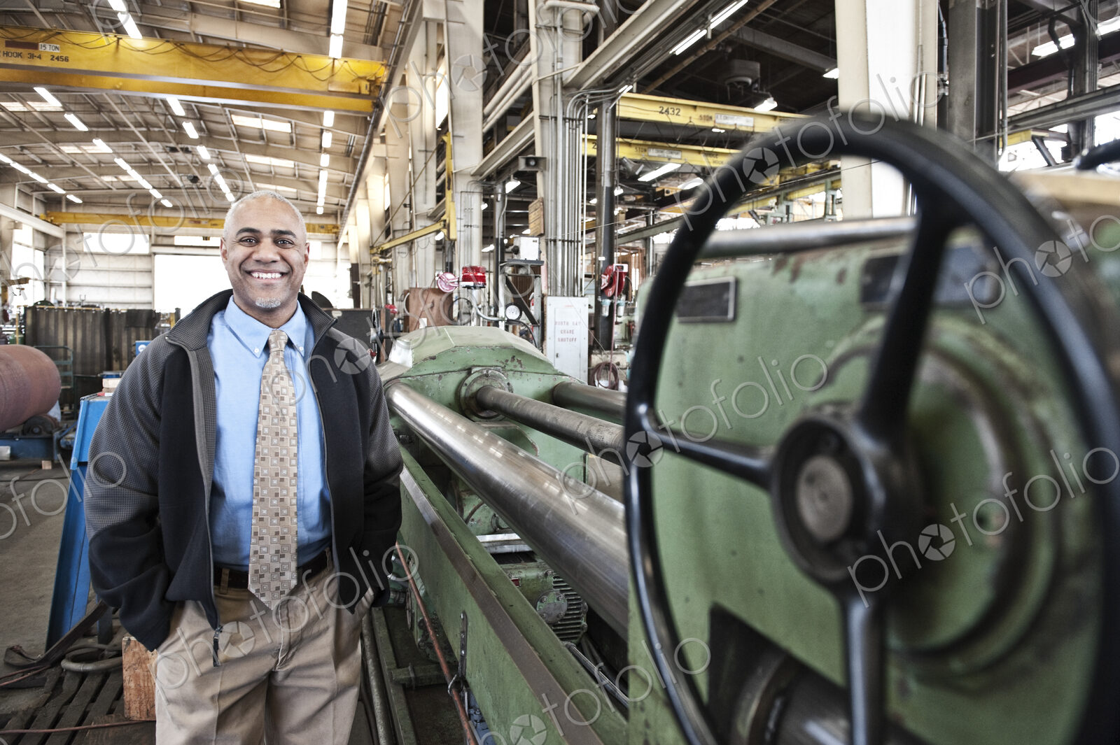 A black man owner of a sheet metal factory satnding on the floor of the factory.