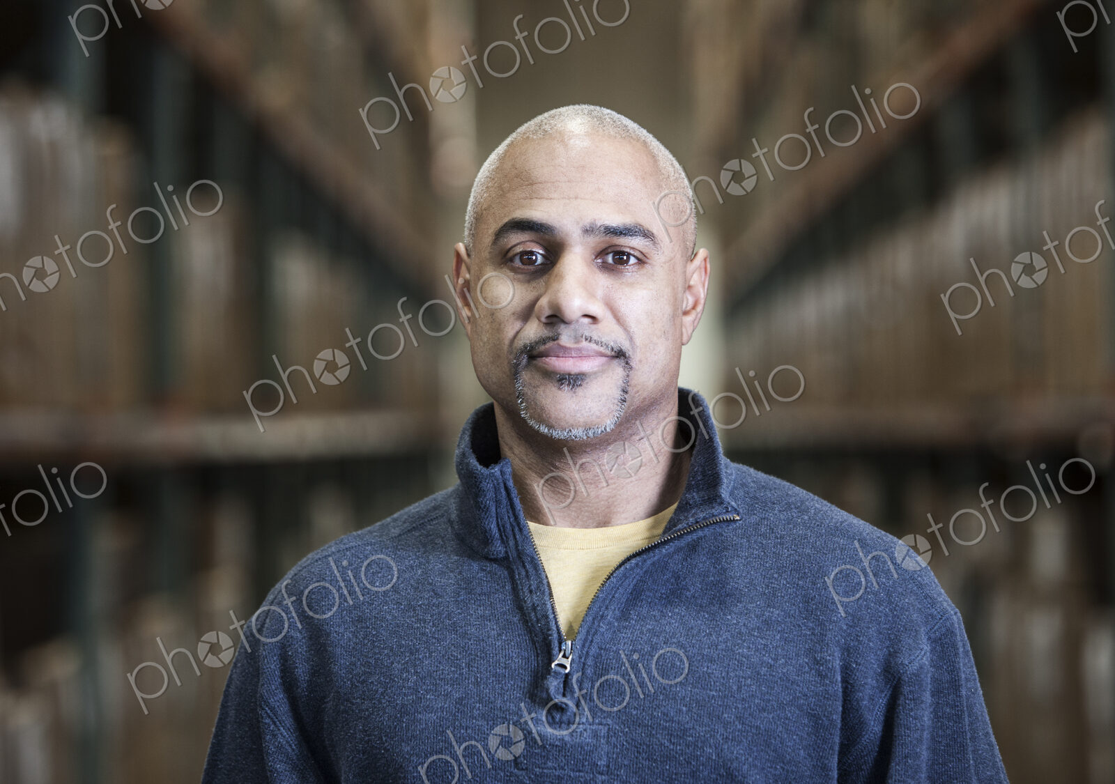 A black warehouse worker standing near boxed products in a distribution warehouse.