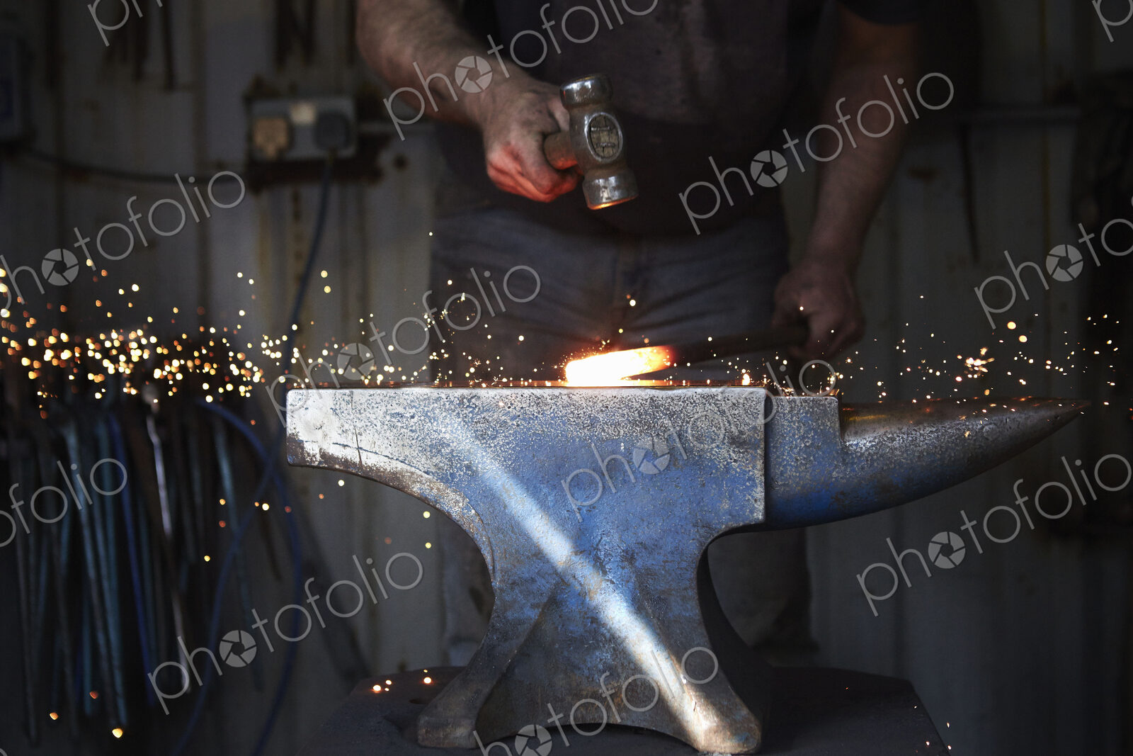 A blacksmith shaping a hot piece of iron on an anvil with a hammer, with sparks flying.