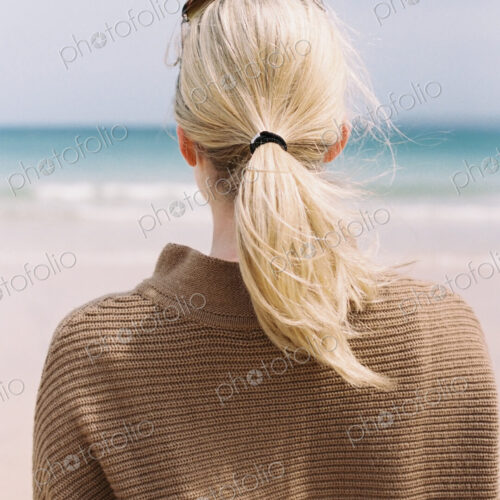A blonde haired woman looking out to sea from the shore. A blonde haired woman looking out to sea from the shore.