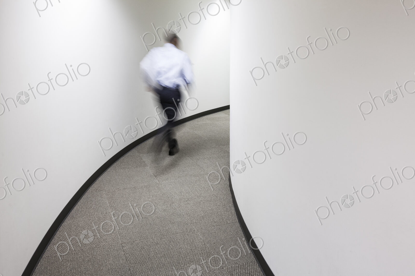 A blur of a businessman running in an office hallway.