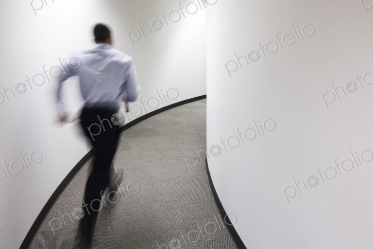 A blur of a businessman running in an office hallway.