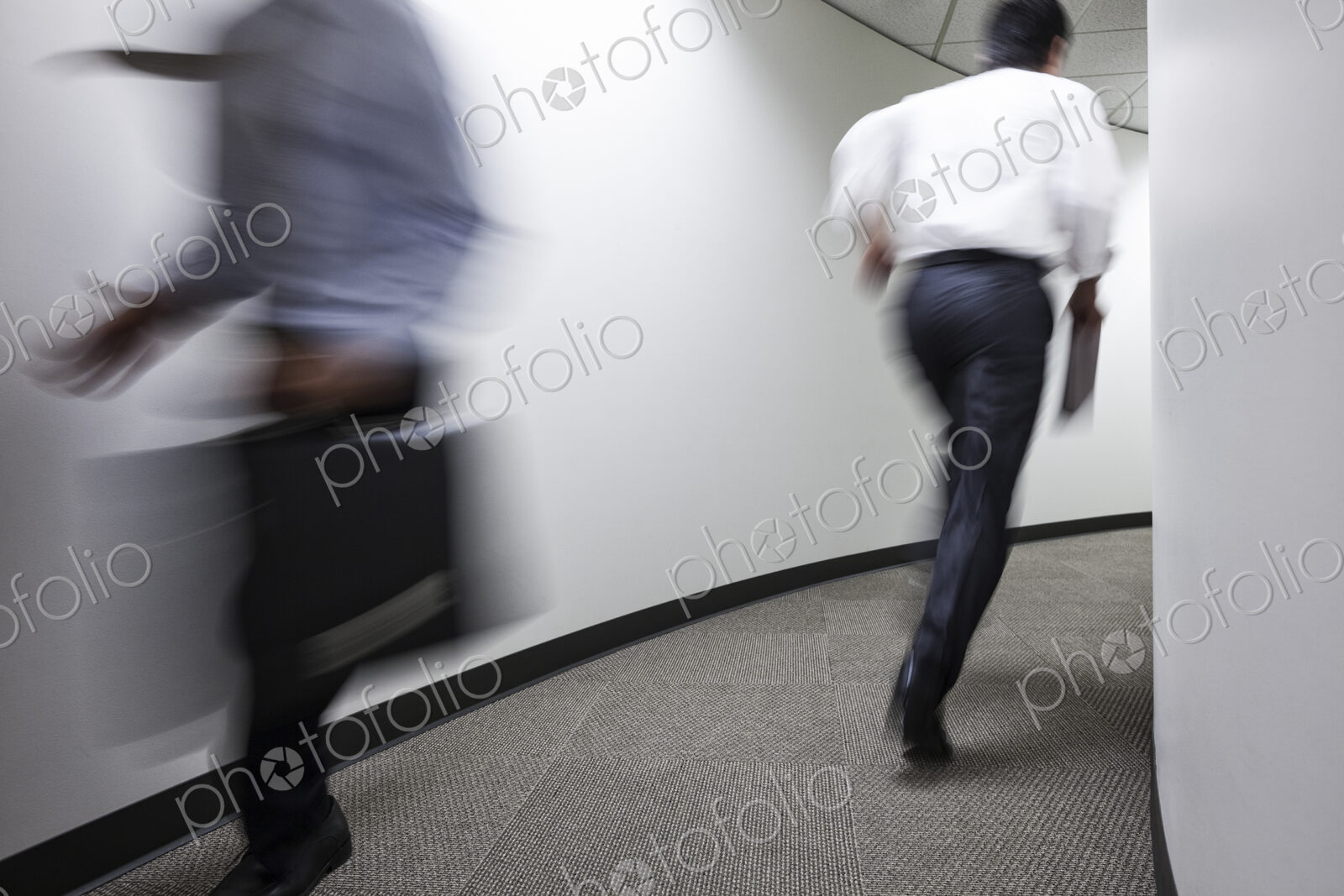 A blur of two businessmen running in an office hallway.