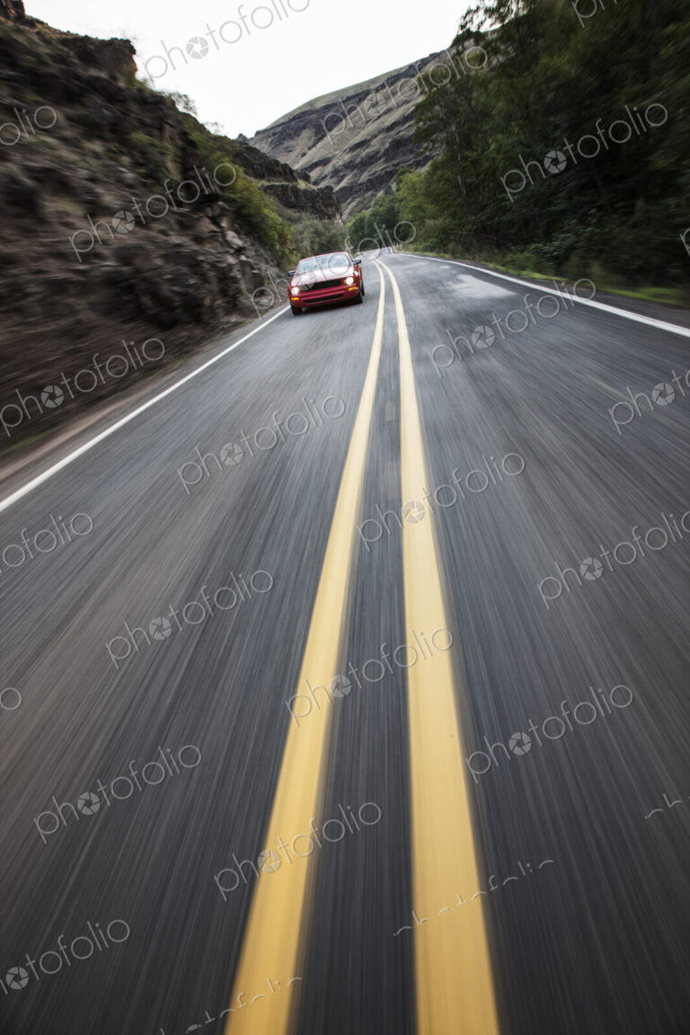 A blurred road and a car traveling along a highway in eastern Washington State, USA.