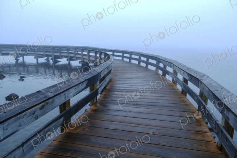 A boardwalk across water, mist rising from the sea.